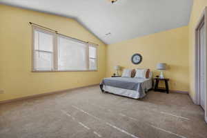 Bedroom with carpet floors and vaulted ceiling