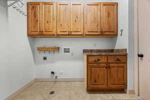 Clothes washing area with cabinets, hookup for a gas dryer, hookup for a washing machine, light tile patterned floors, and hookup for an electric dryer