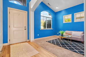 Foyer featuring wood-type flooring and lofted ceiling