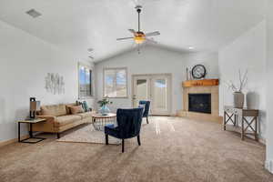 Living room with carpet flooring, a textured ceiling, vaulted ceiling, ceiling fan, and a tile fireplace