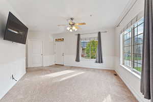 Empty room featuring plenty of natural light, ceiling fan, and light carpet