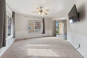 Carpeted empty room with ceiling fan and a healthy amount of sunlight