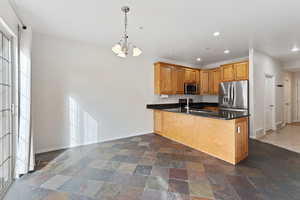 Kitchen with sink, hanging light fixtures, kitchen peninsula, a chandelier, and appliances with stainless steel finishes