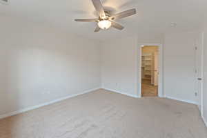 Empty room with ceiling fan and light colored carpet