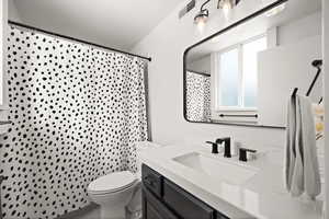 Bathroom with a shower with curtain, vanity, toilet, and tile patterned floors