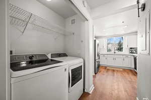 Laundry area with light wood-type flooring, a barn door, and separate washer and dryer