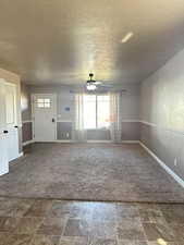 Carpeted empty room with a textured ceiling and ceiling fan