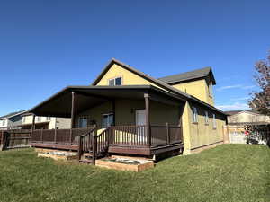 Rear view of house with a wooden deck and a yard