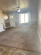 Interior space featuring ceiling fan, dark carpet, and a textured ceiling