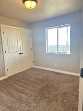 Unfurnished bedroom with carpet, a textured ceiling, and a closet