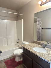 Full bathroom with tile patterned floors, a textured ceiling, toilet, shower / tub combo with curtain, and vanity