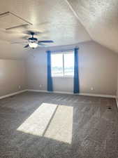 Bonus room with vaulted ceiling, ceiling fan, carpet floors, and a textured ceiling