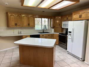 Kitchen with a center island, sink, light tile patterned flooring, and white appliances