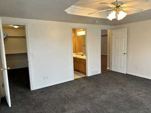 Unfurnished bedroom with carpet flooring, ensuite bath, sink, a walk in closet, and a closet