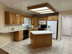 Kitchen with sink, a center island, black appliances, and light tile patterned floors