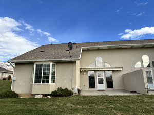 Back of property with a lawn and a patio