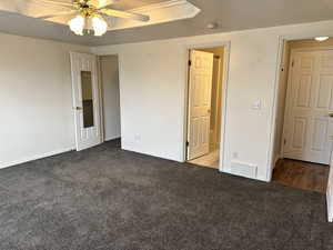 Unfurnished bedroom featuring ceiling fan, a textured ceiling, and dark colored carpet