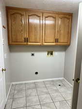 Clothes washing area featuring electric dryer hookup, light tile patterned flooring, cabinets, and washer hookup