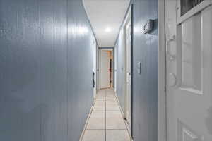 Corridor with wooden walls and light tile patterned flooring