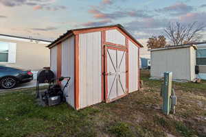 Outdoor structure at dusk featuring a yard