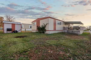 Property exterior at dusk with a storage shed and a lawn