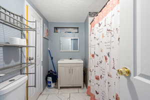 Bathroom with vanity, a textured ceiling, and toilet