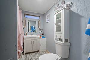 Bathroom with vanity, a textured ceiling, toilet, and ornamental molding