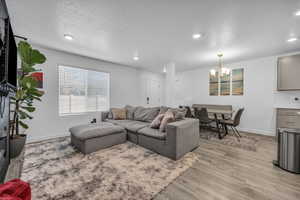 Living room with a textured ceiling, light hardwood / wood-style floors, and a notable chandelier