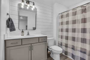 Bathroom with walk in shower, vanity, hardwood / wood-style flooring, toilet, and wood walls