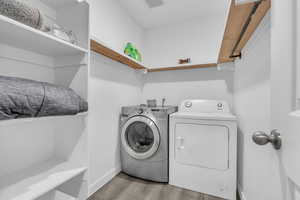 Laundry room with washing machine and dryer and light hardwood / wood-style floors