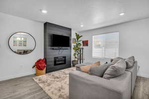 Living room featuring a textured ceiling, a fireplace, and light hardwood / wood-style flooring