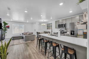 Kitchen featuring a breakfast bar area, gray cabinets, and appliances with stainless steel finishes