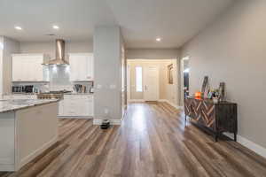 Kitchen featuring wall chimney exhaust hood, dark hardwood / wood-style floors, and white cabinetry