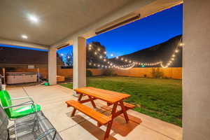 Patio at night with a hot tub and a lawn