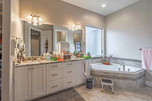 Bathroom featuring tile patterned flooring, vanity, and tiled tub