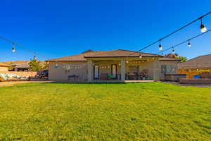 Rear view of house featuring a patio and a lawn