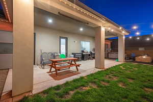 Patio at twilight featuring a yard and a hot tub