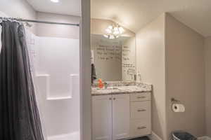 Bathroom featuring vanity, vaulted ceiling, and curtained shower