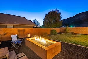 Patio terrace at dusk with a lawn and a fire pit