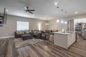 Kitchen featuring light stone counters, white cabinetry, a kitchen island with sink, and stainless steel appliances