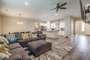 Living room with light hardwood / wood-style flooring and ceiling fan with notable chandelier