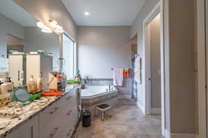 Bathroom with vanity and tiled bath