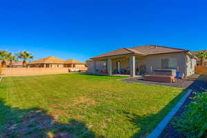 Back of property with a patio area, a yard, and a hot tub