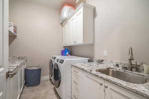 Laundry room with washer and clothes dryer, cabinets, and sink