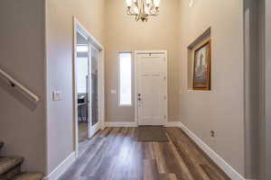 Foyer with dark hardwood / wood-style flooring and an inviting chandelier