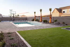 Pool at dusk with basketball court and a yard