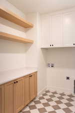 Laundry area with cabinets, hookup for a washing machine, and electric dryer hookup