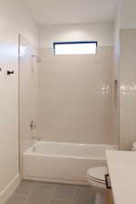 Full bathroom with tile patterned flooring, tiled shower / bath combo, toilet, and vanity