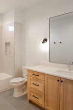 Full bathroom featuring tile patterned flooring, vanity, tiled shower / bath combo, and toilet