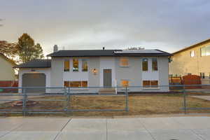 Raised ranch featuring solar panels, a yard, and a garage